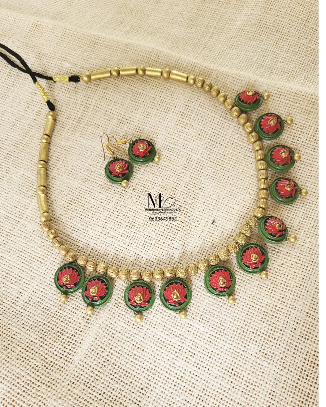 Handmade terracotta necklace set featuring Red lotus motifs with matching earrings on a natural fabric background.